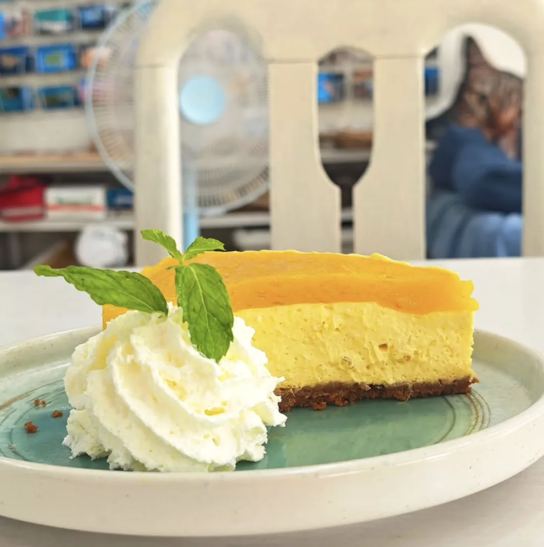 Mango cheesecake slice with whipped cream and mint